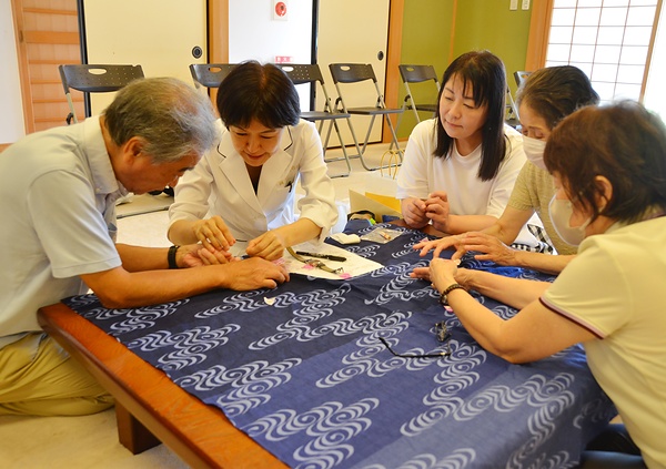 山口氏（左から2人目）にきゅうの使い方やつぼの刺激の仕方を教わる参加者