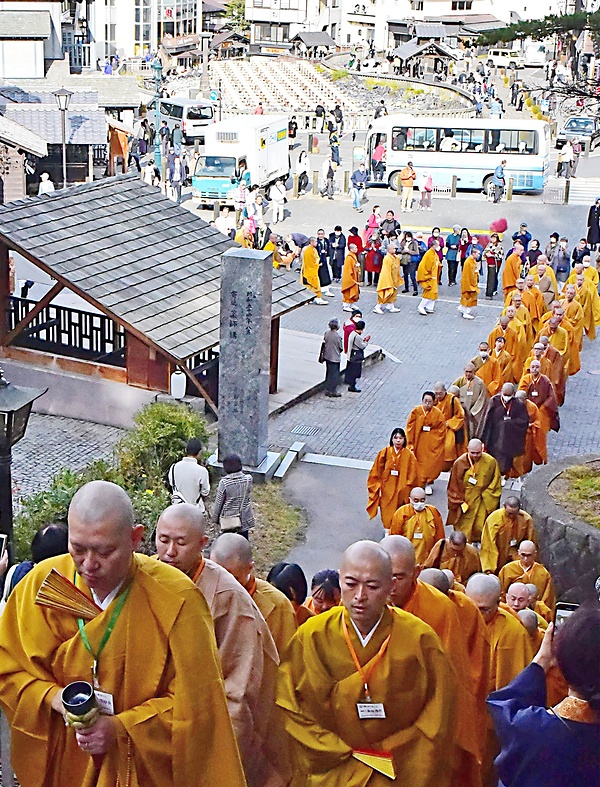 約100人の青年僧が温泉街を練り、光泉寺に向かった。奥に見えるのは「湯畑」