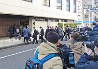 報道陣が取り囲む教団本部に入る清算手続きの関係者ら